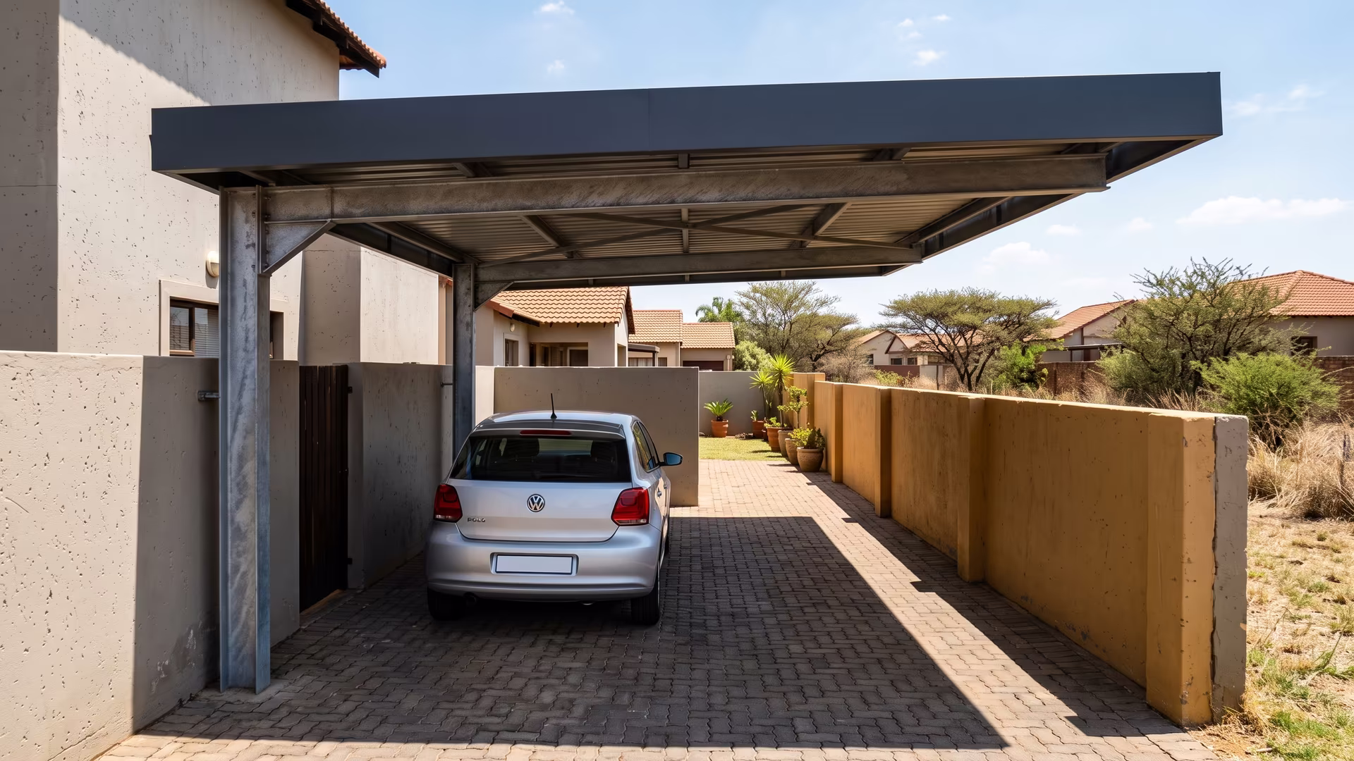 Cantilever steel carport over a narrow townhouse driveway in a Centurion complex