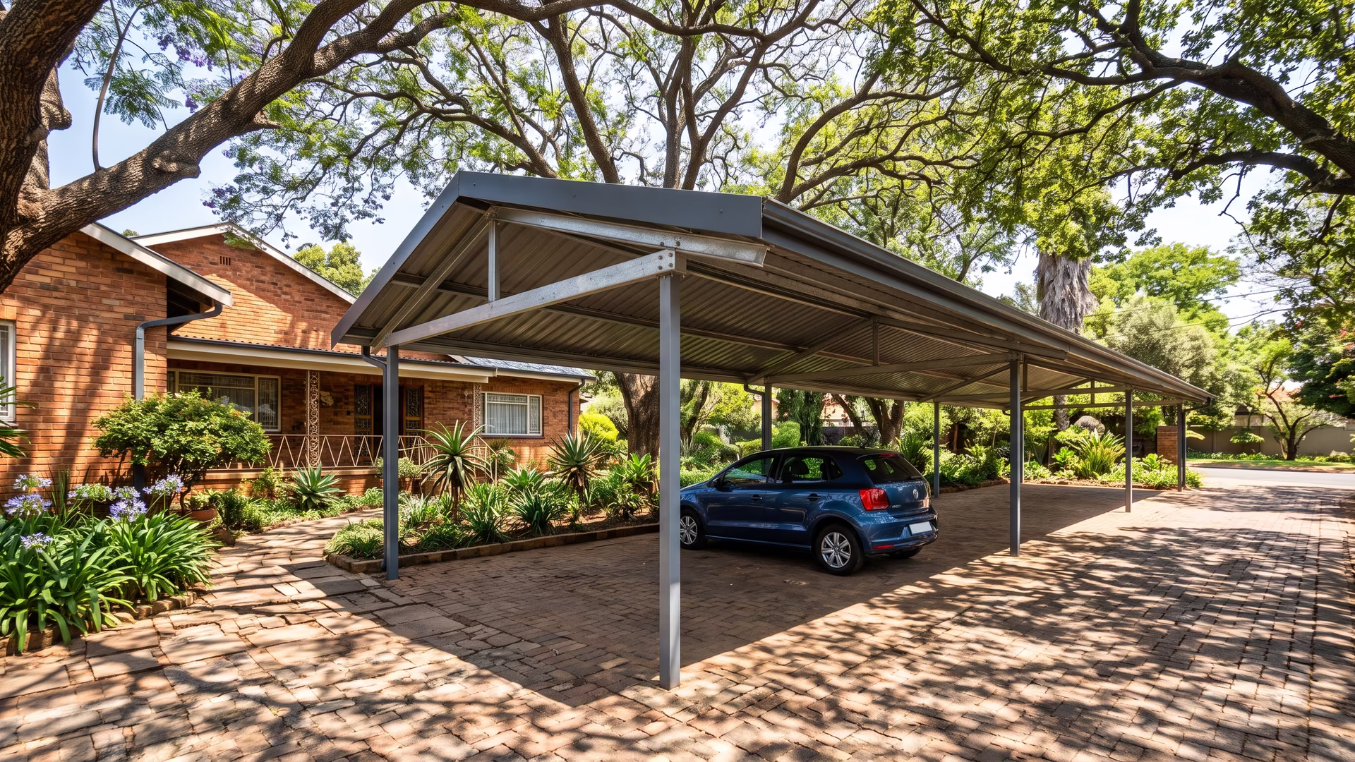 Long-span carport with a pitched charcoal roof under mature jacaranda trees at an older Waterkloof home