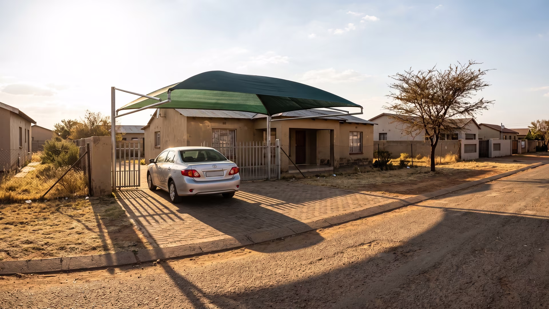Shade net carport over a car on a compact freehold driveway in Pretoria West in low afternoon sun