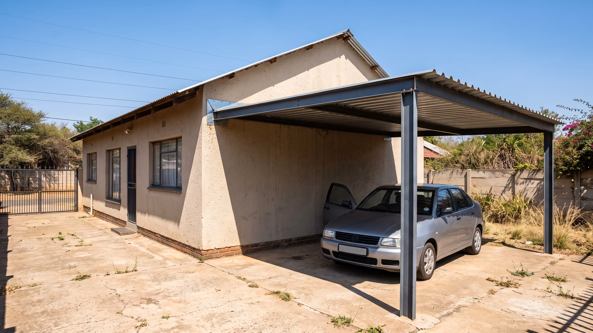 Lean-to carport fixed to the wall of a plastered Pretoria house with flashing at the wall and posts on the outer side only
